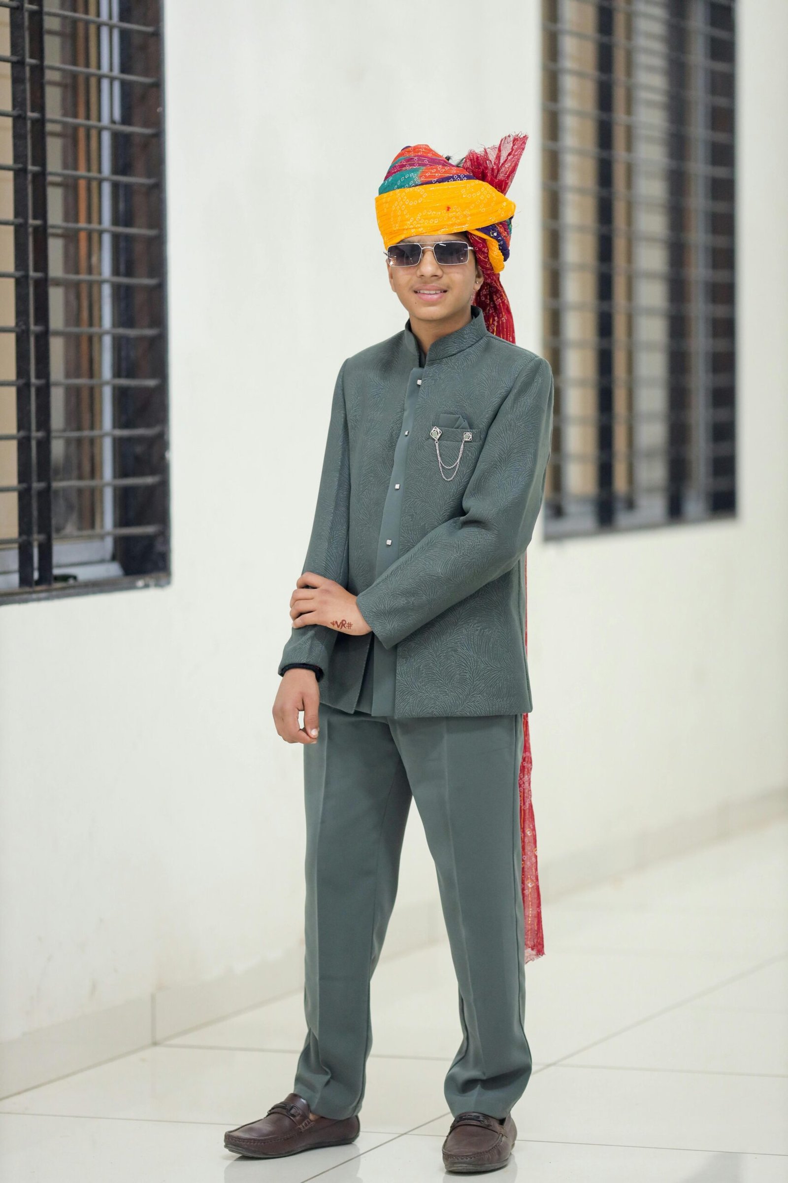 Portrait of a young man wearing traditional Indian clothing and sunglasses indoors.