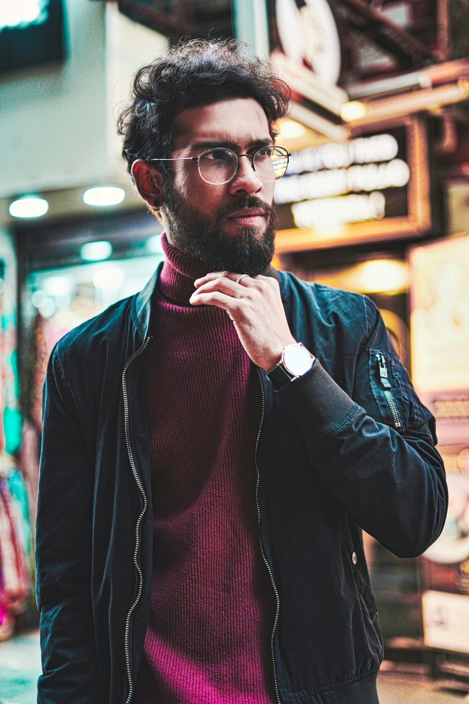 Portrait of a stylish man with glasses in an urban street setting, showcasing modern fashion.